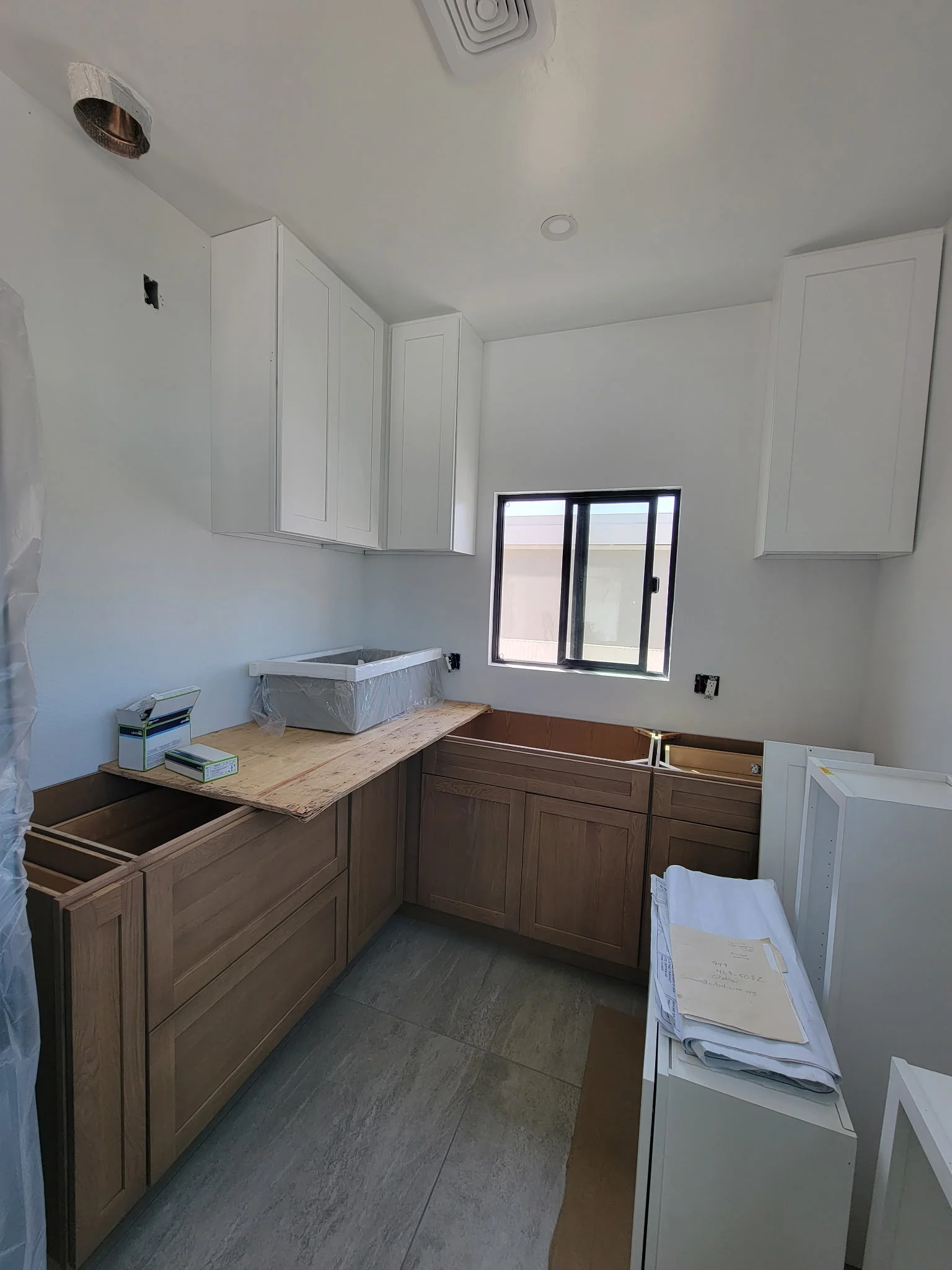 Kitchen remodel with dark wood lower cabinets, white upper cabinets, and new window