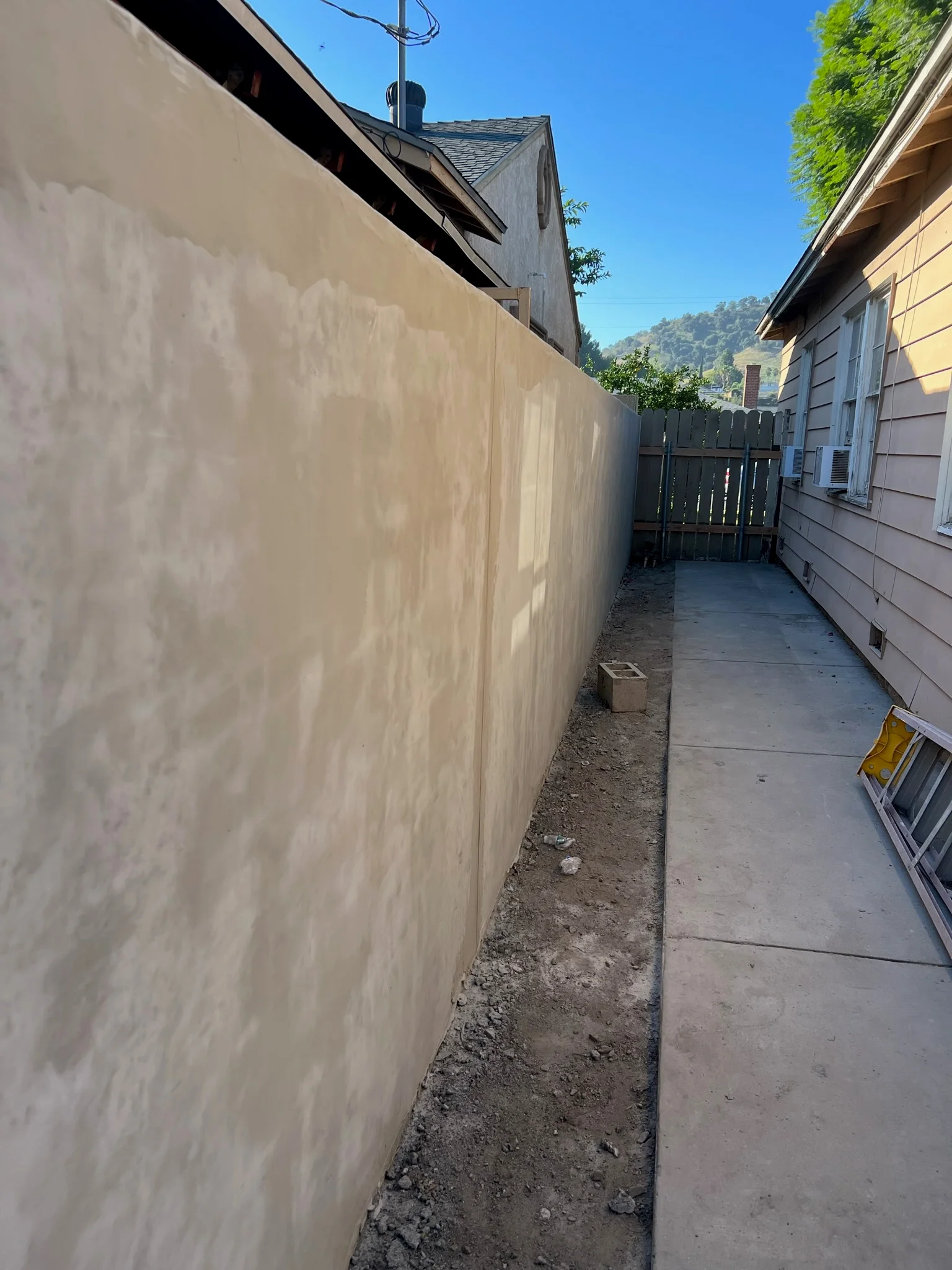 Concrete pathway and cream-colored retaining wall along residential side yard