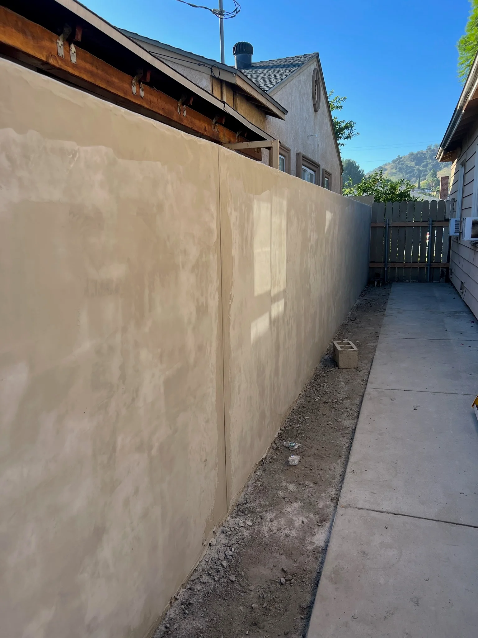 Newly constructed concrete retaining wall along residential side yard with finished surface