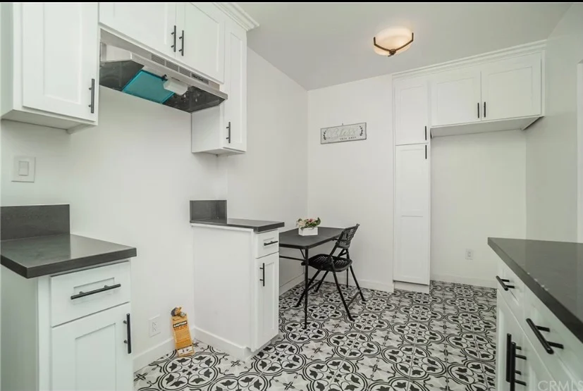 Modern kitchen with white cabinets, gray counters, and patterned tile flooring