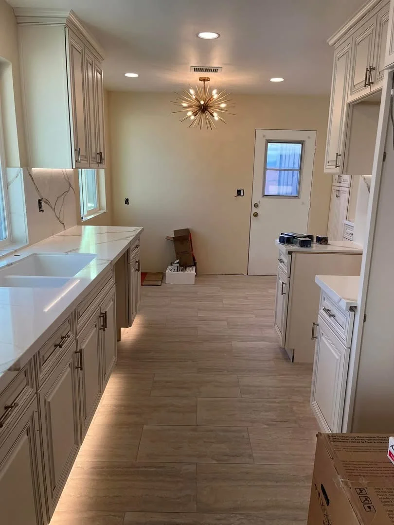 Newly renovated kitchen with white cabinetry, quartz counters, and wood-look tile flooring
