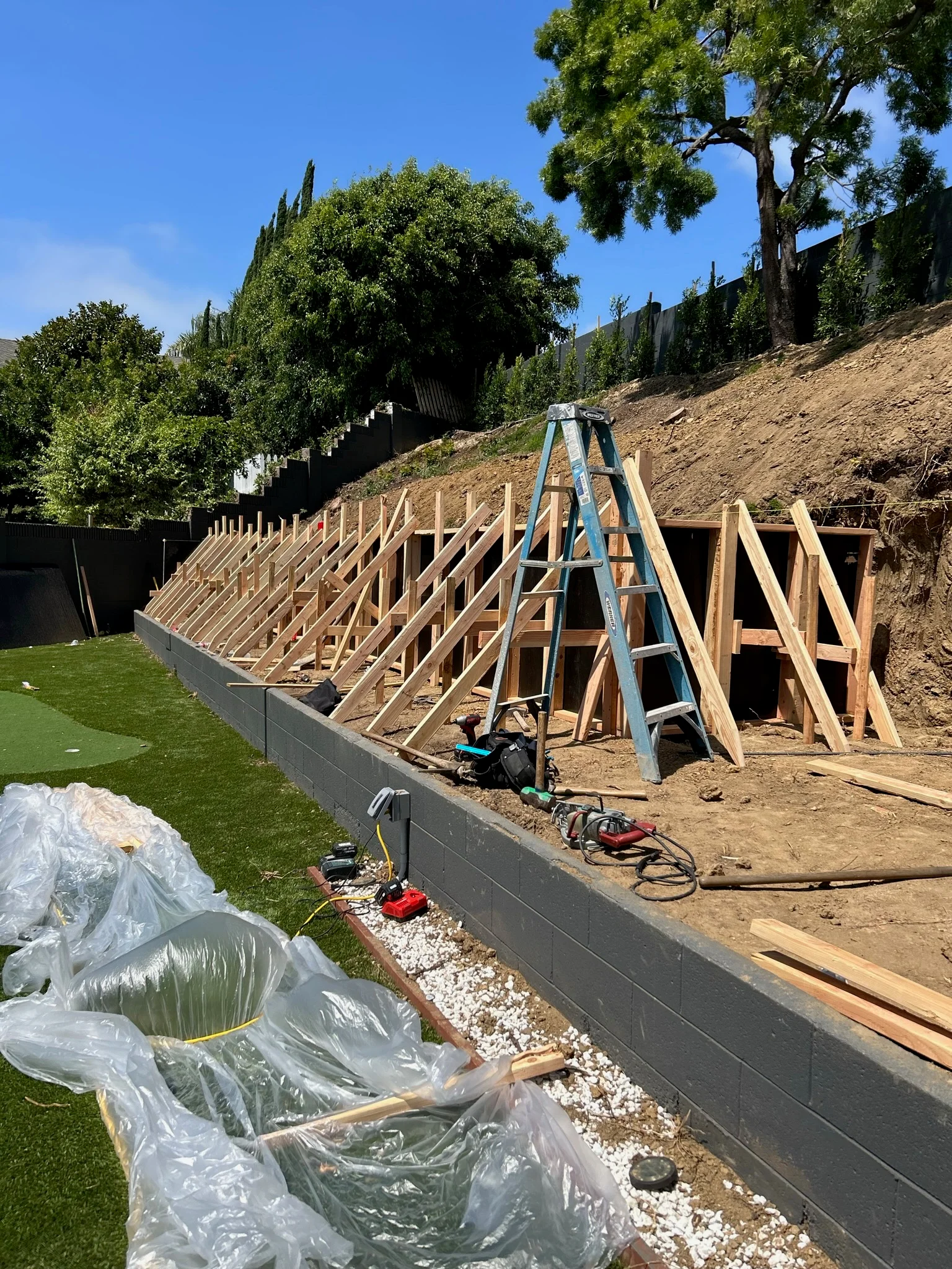 Wood framing structure on hillside with concrete foundation and retaining wall during construction