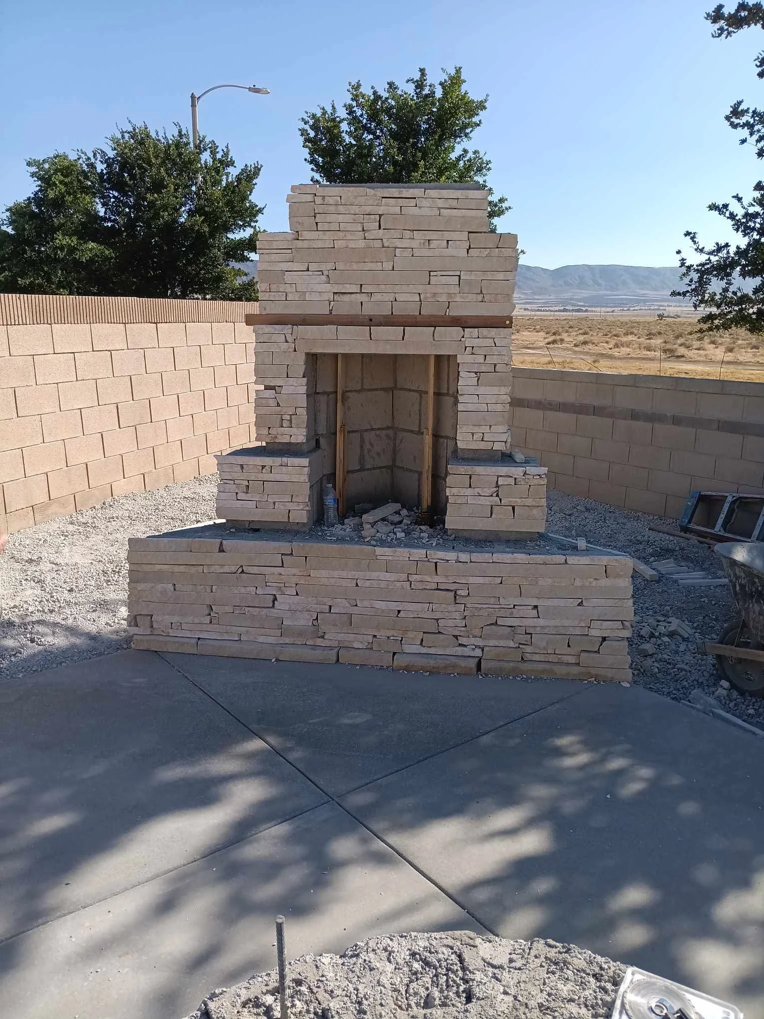 Completed masonry fireplace with stone veneer and arched opening in residential backyard