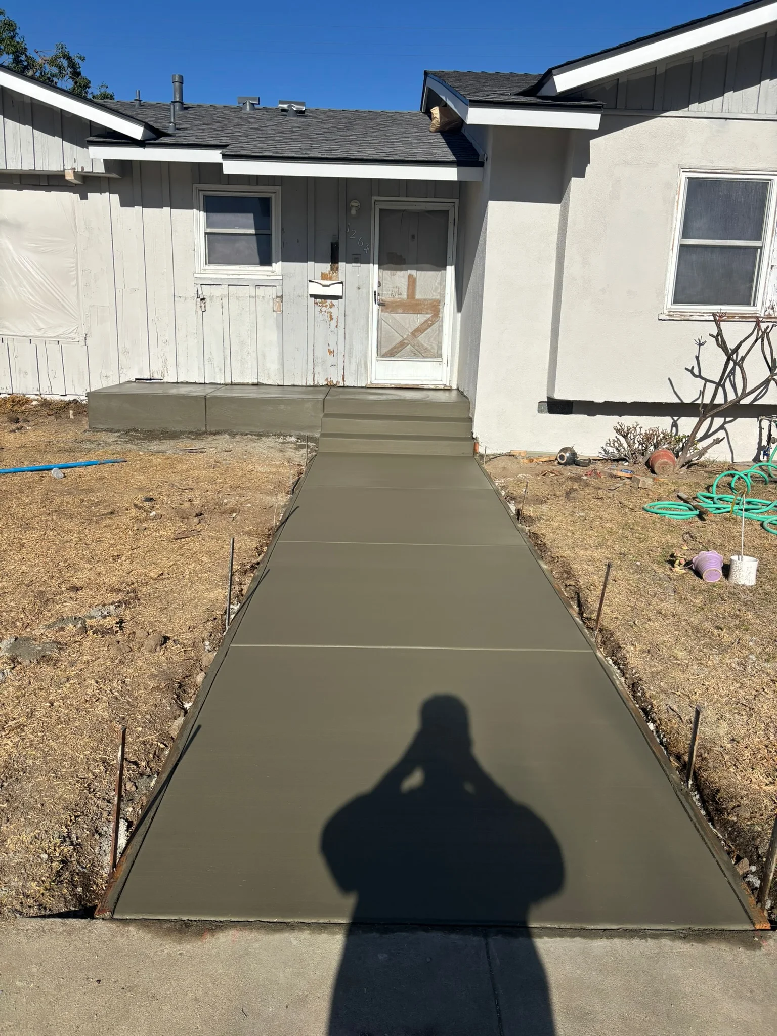 Newly poured concrete walkway with control joints leading to residential home entrance