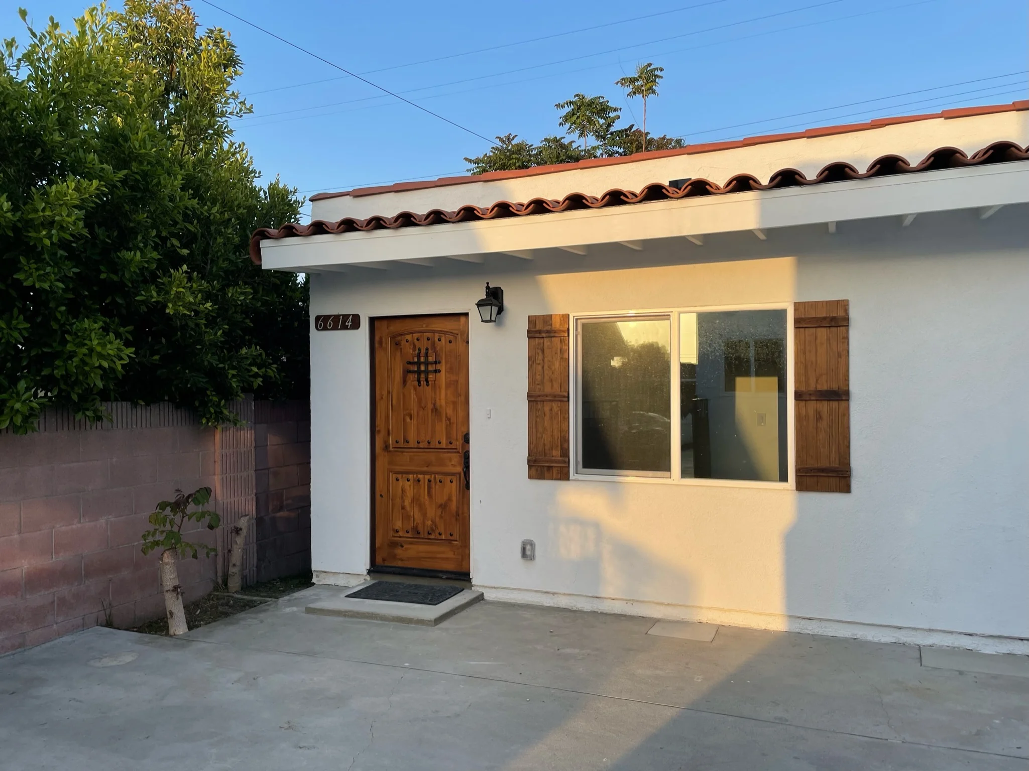 White stucco Spanish Colonial home with clay tile roof, wooden door, and new windows