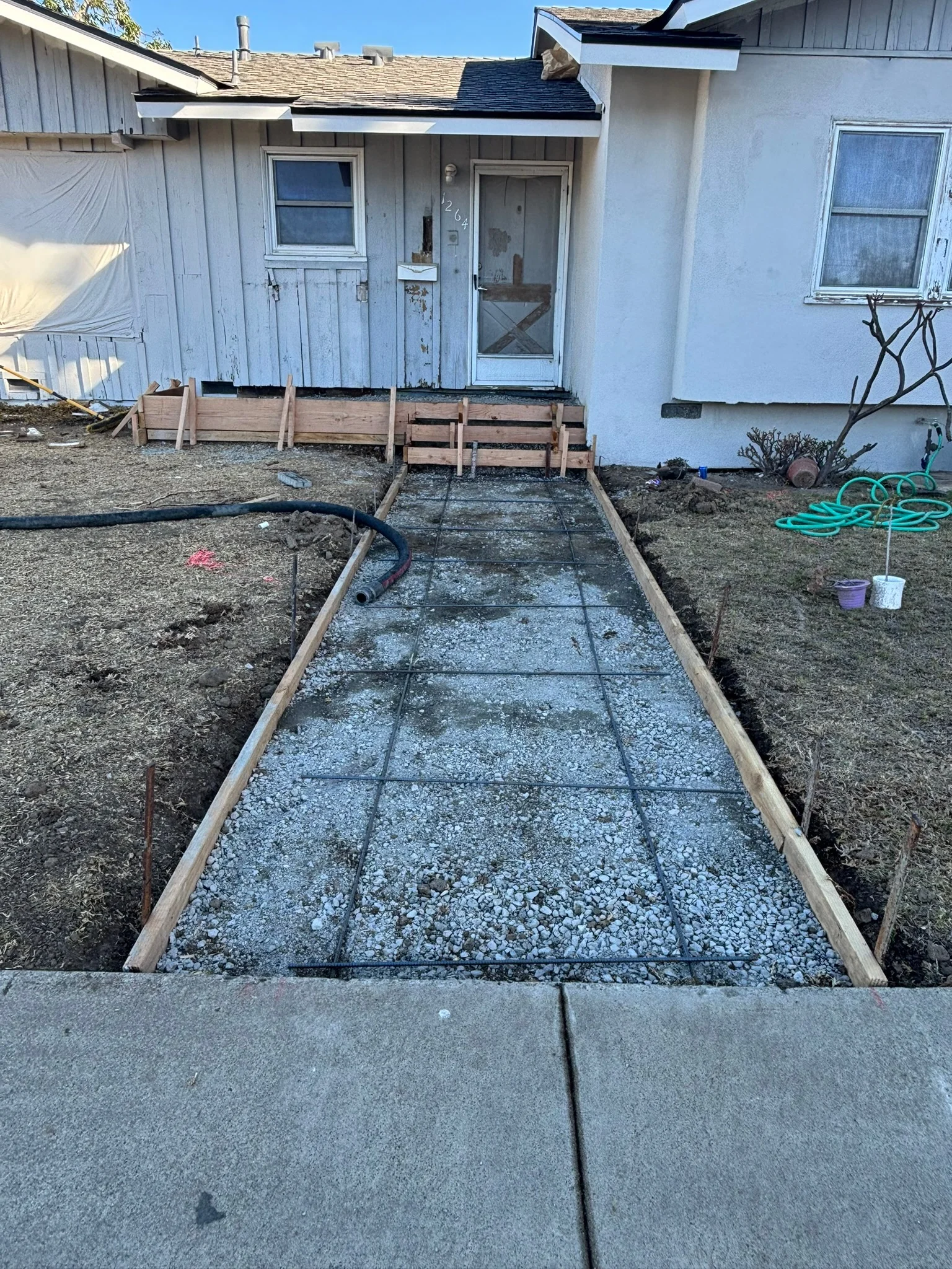 Newly constructed gravel walkway with wooden frame borders leading to residential home entrance