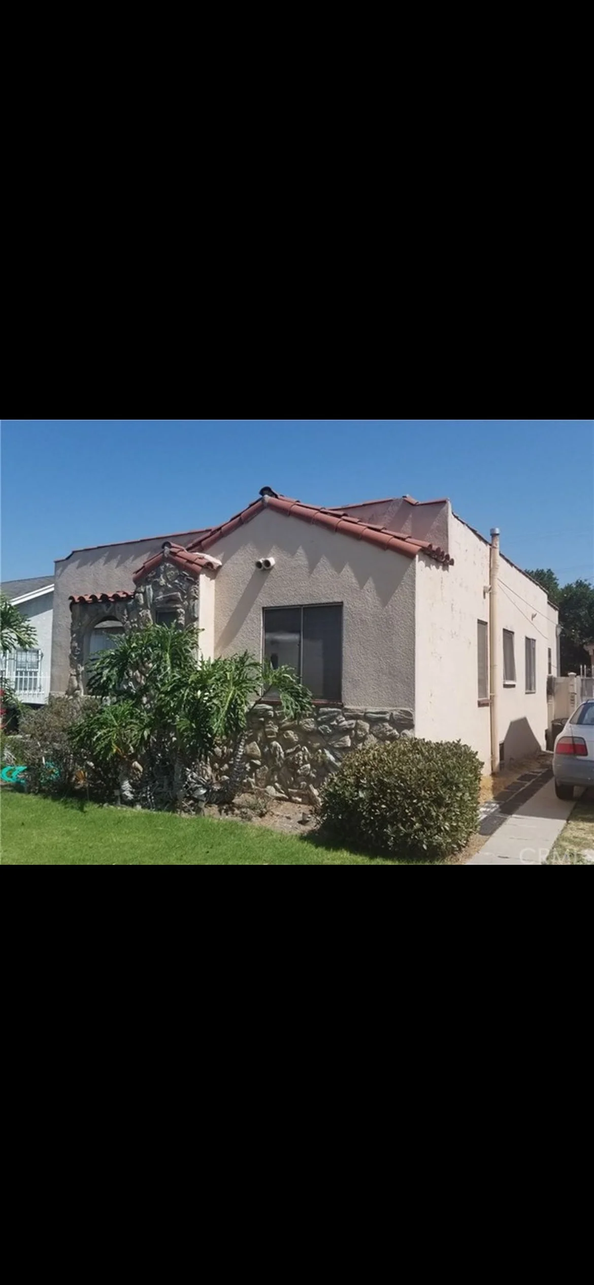 Spanish Colonial home with cream stucco walls, clay tile roof, and manicured landscaping