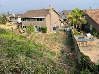 Two-story home with new roof and siding, cleared yard with palm tree and patio area