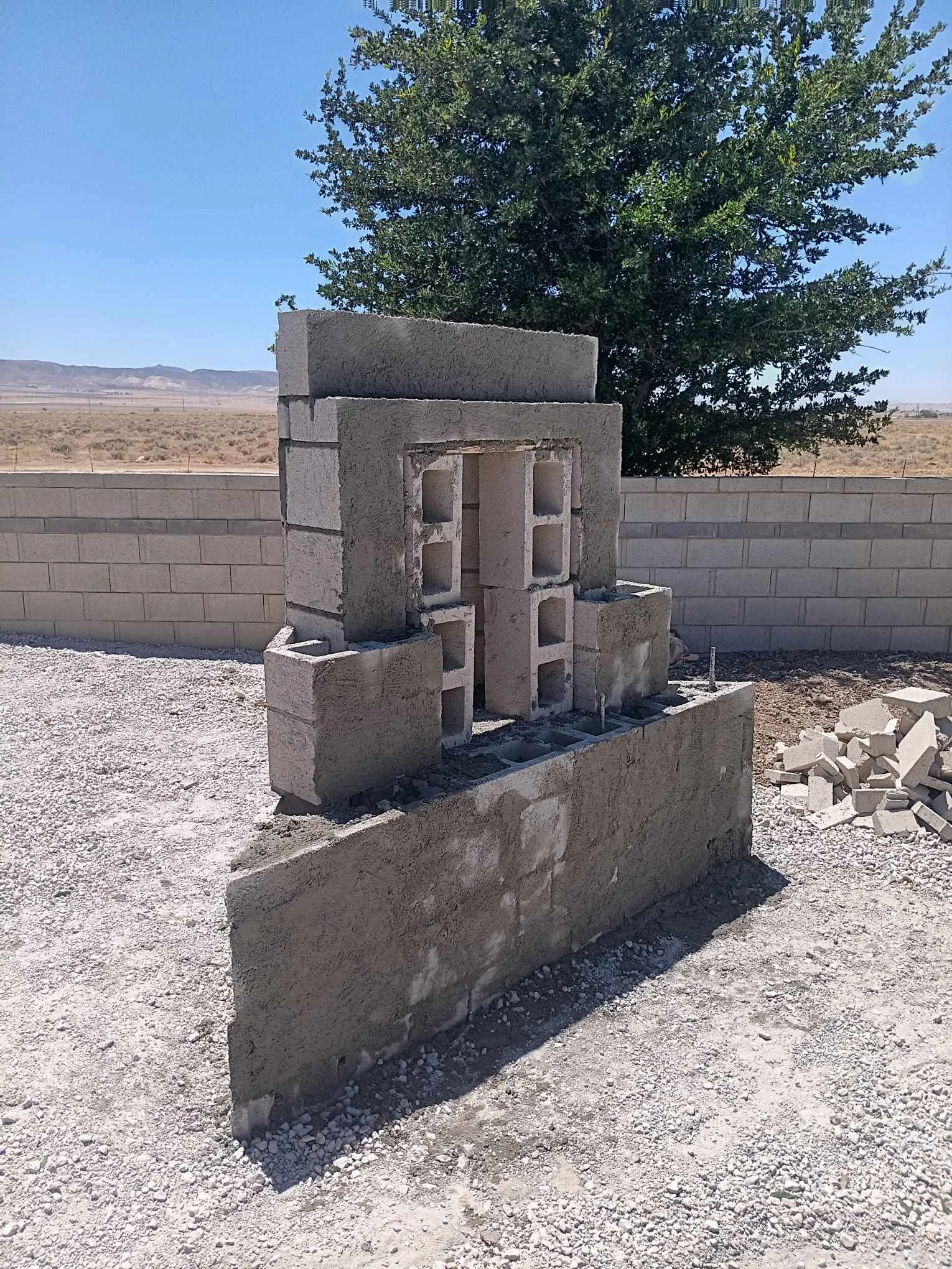 Newly constructed concrete block chimney with reinforced cap and foundation base