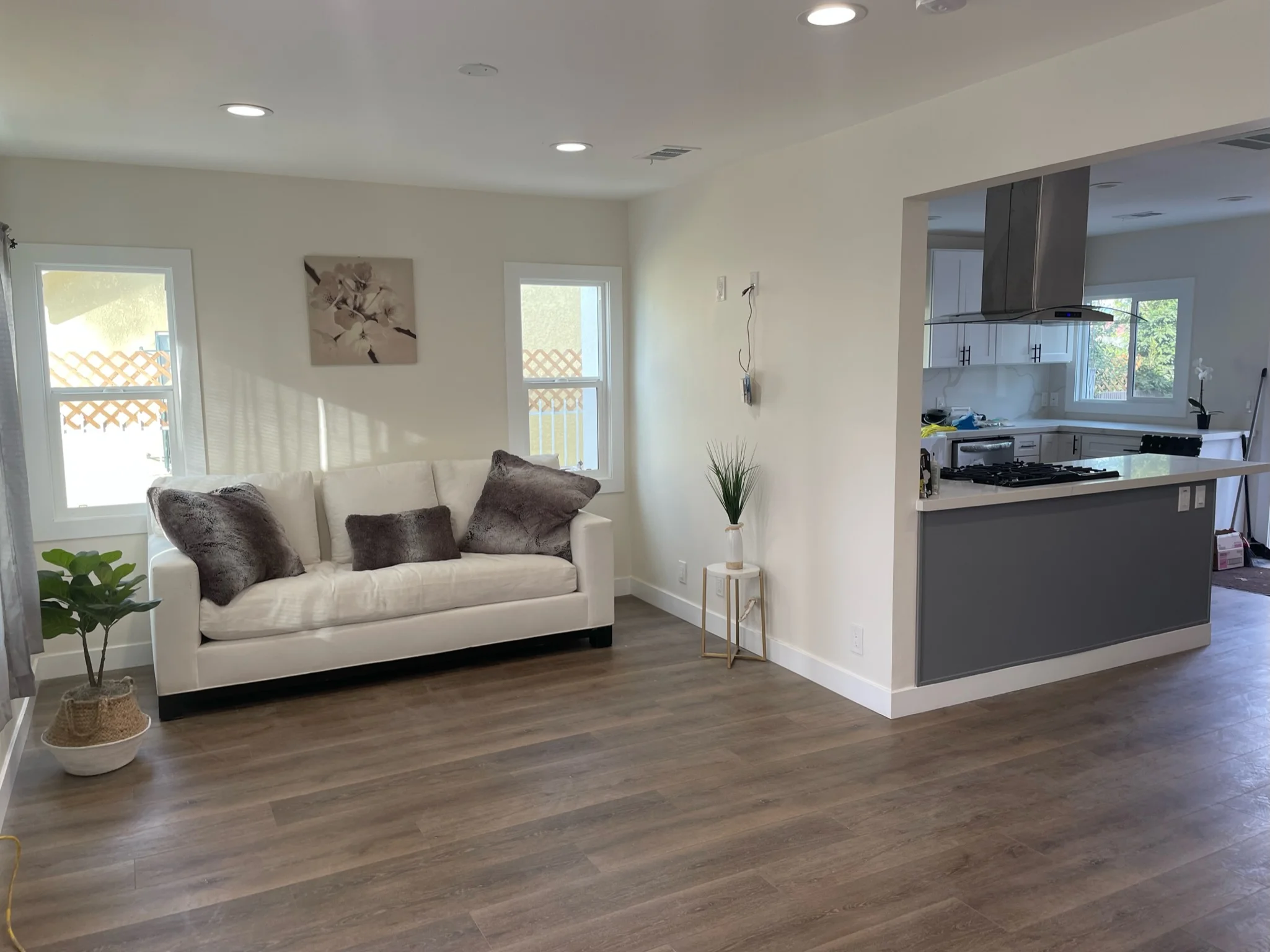 Modern open-concept living room and kitchen with cream sofa, dark cabinetry, and wood flooring
