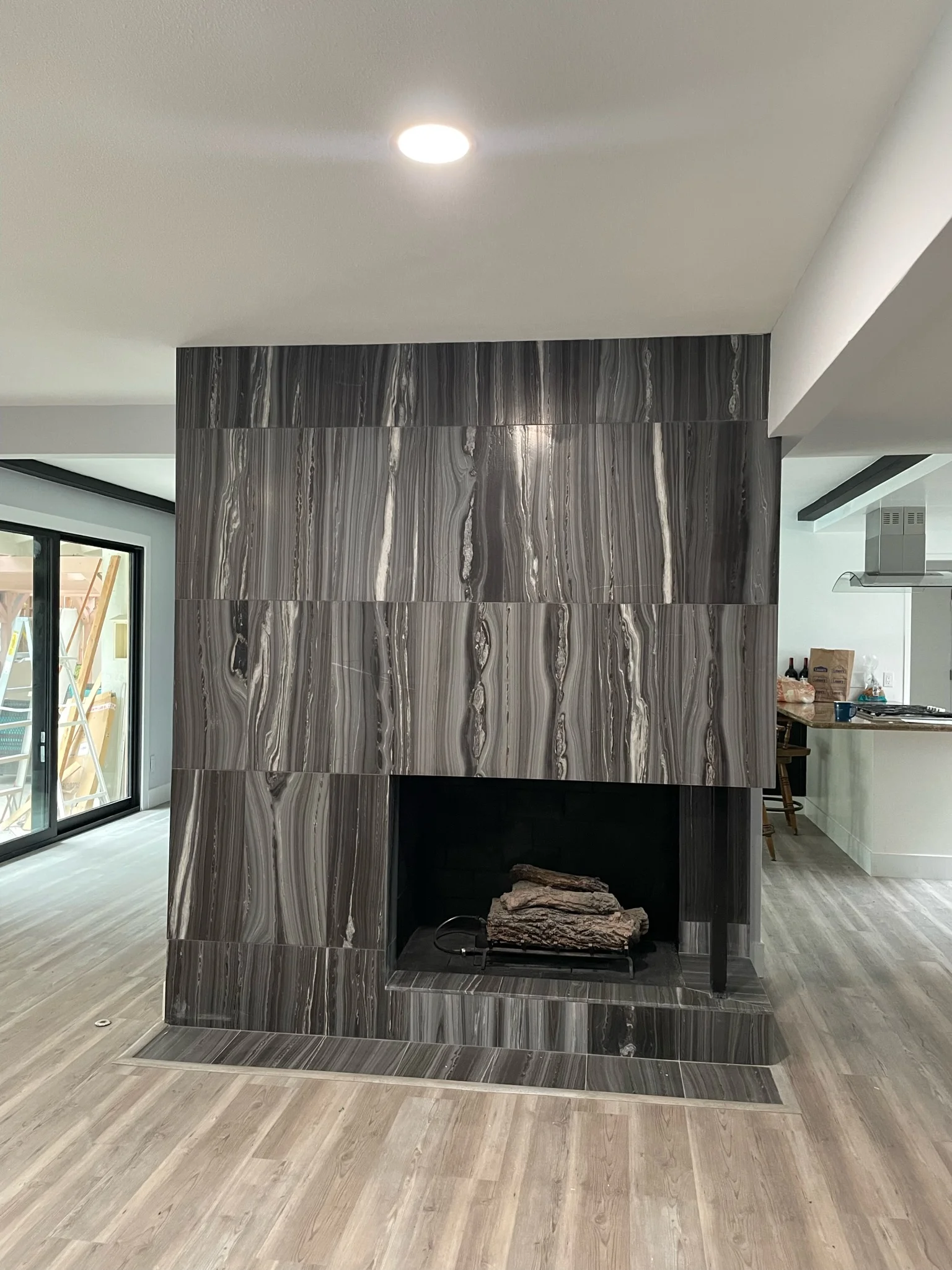 Gray marble tile fireplace feature wall with geometric pattern and recessed fireplace opening