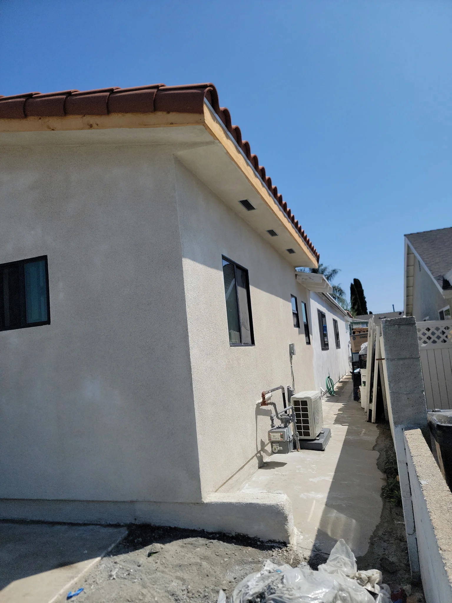 White stucco residential addition with clay tile roof and casement windows