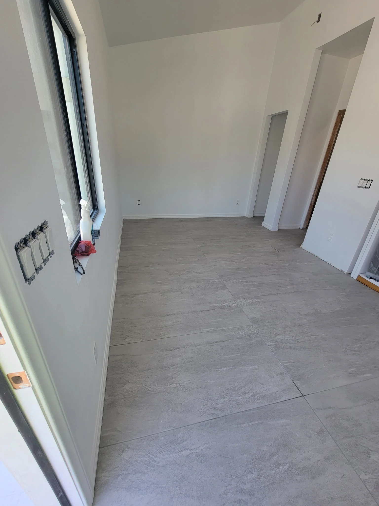 Renovated interior room with gray vinyl plank flooring, white walls, and new electrical outlets