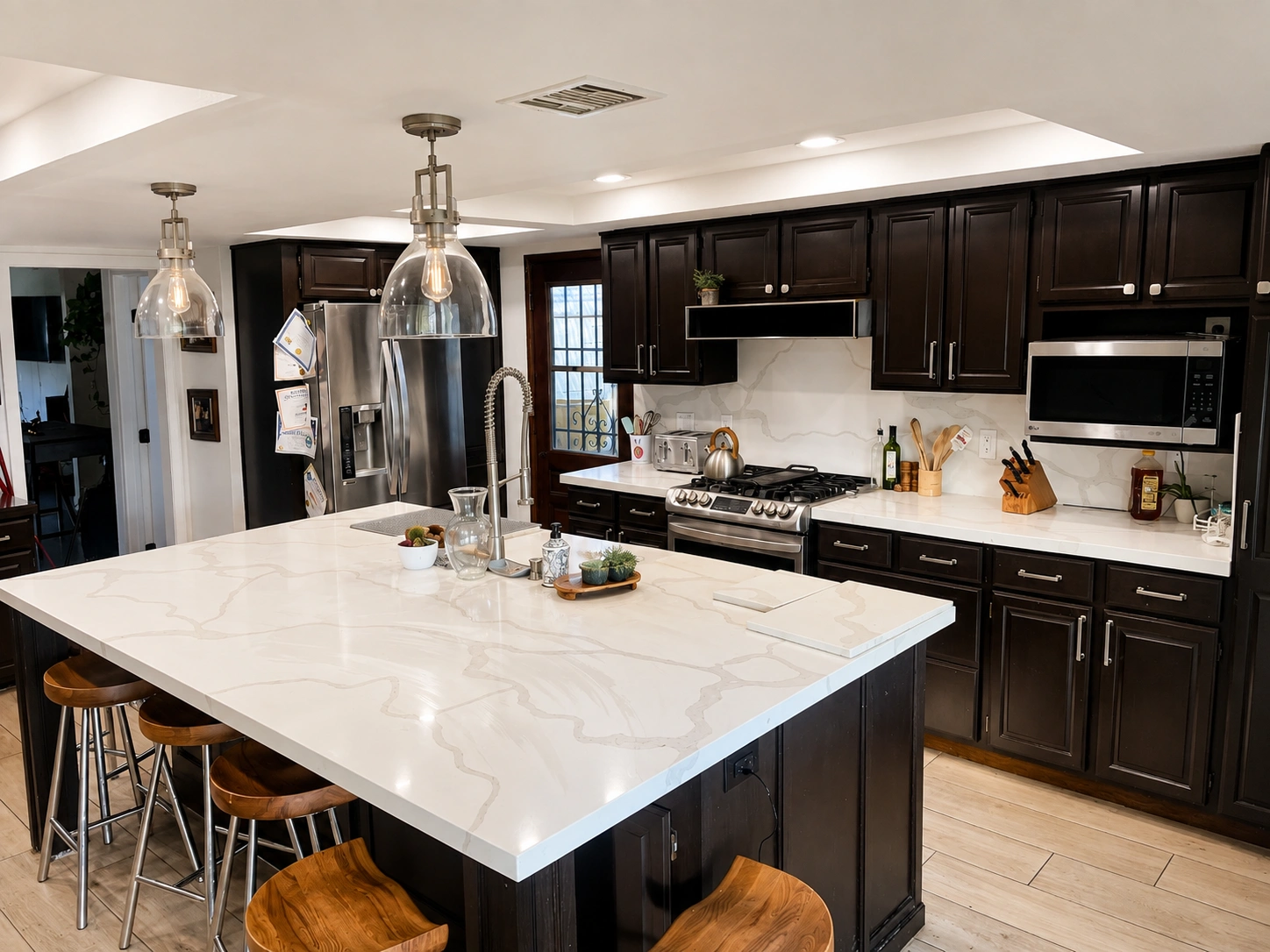 Remodeled kitchen with large stone island and dark cabinetry built by Rehab Building Co. INC